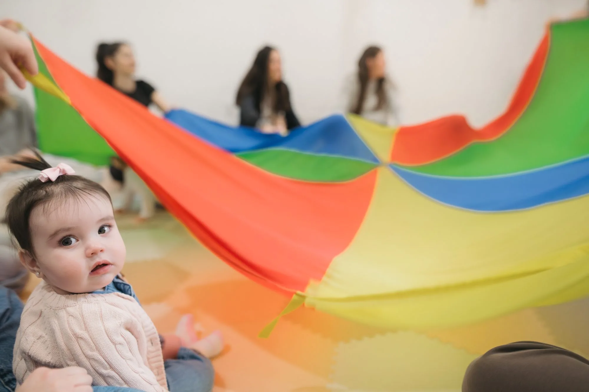 Baby girl close-up under rainbow parachute at Rockin' with Rach Toronto music class