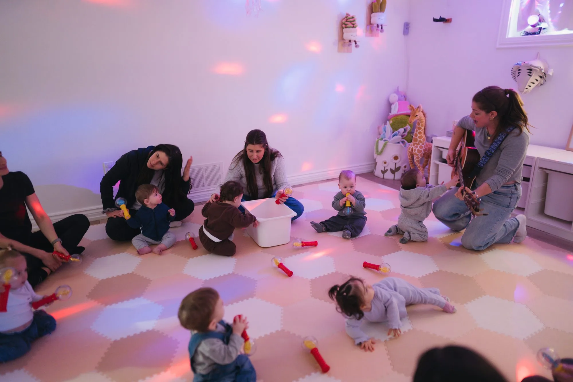 Rachel playing live guitar for babies holding light wands at Rockin' with Rach Toronto