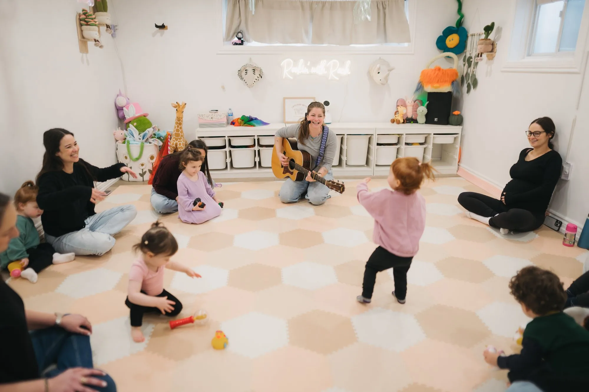 Rachel Kornblum playing guitar for a wide circle of families at Rockin' with Rach studio Toronto