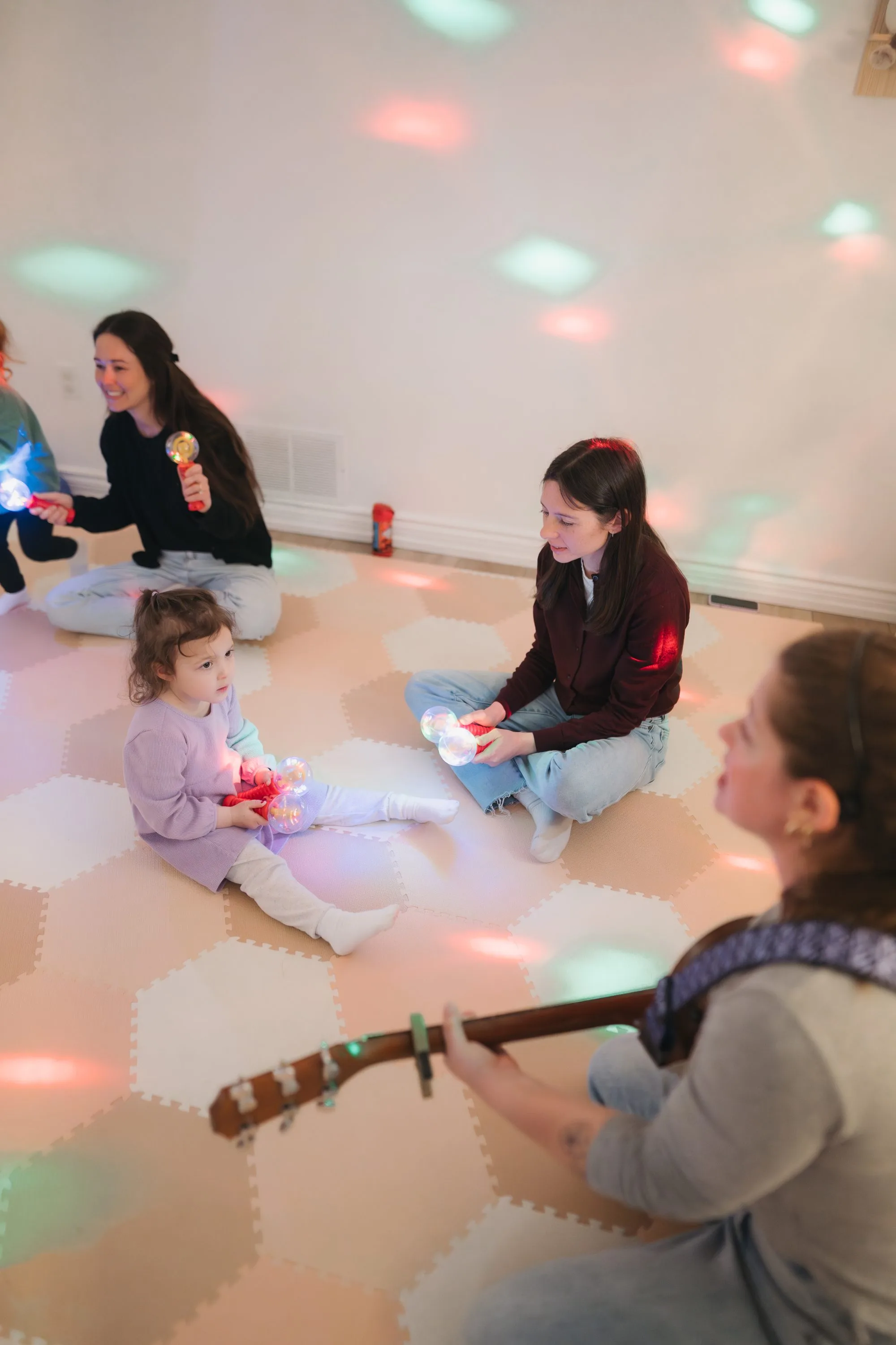 Rachel leading a toddler and caregiver through a light show at Rockin' with Rach Toronto