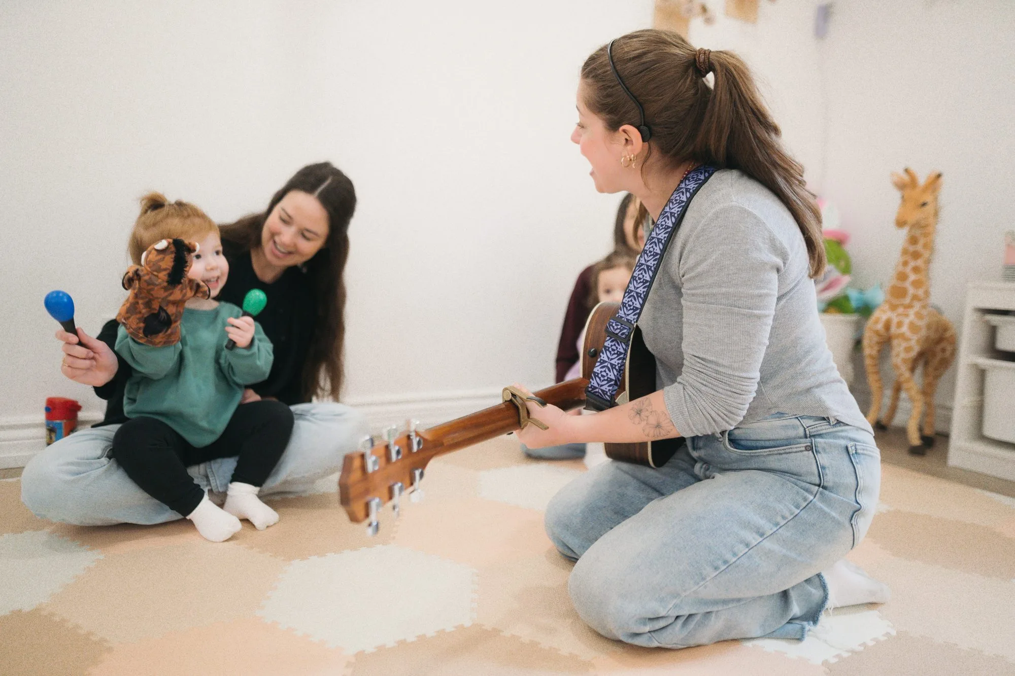 Rachel with a toddler, puppet, and guitar at Rockin' with Rach baby music class Toronto