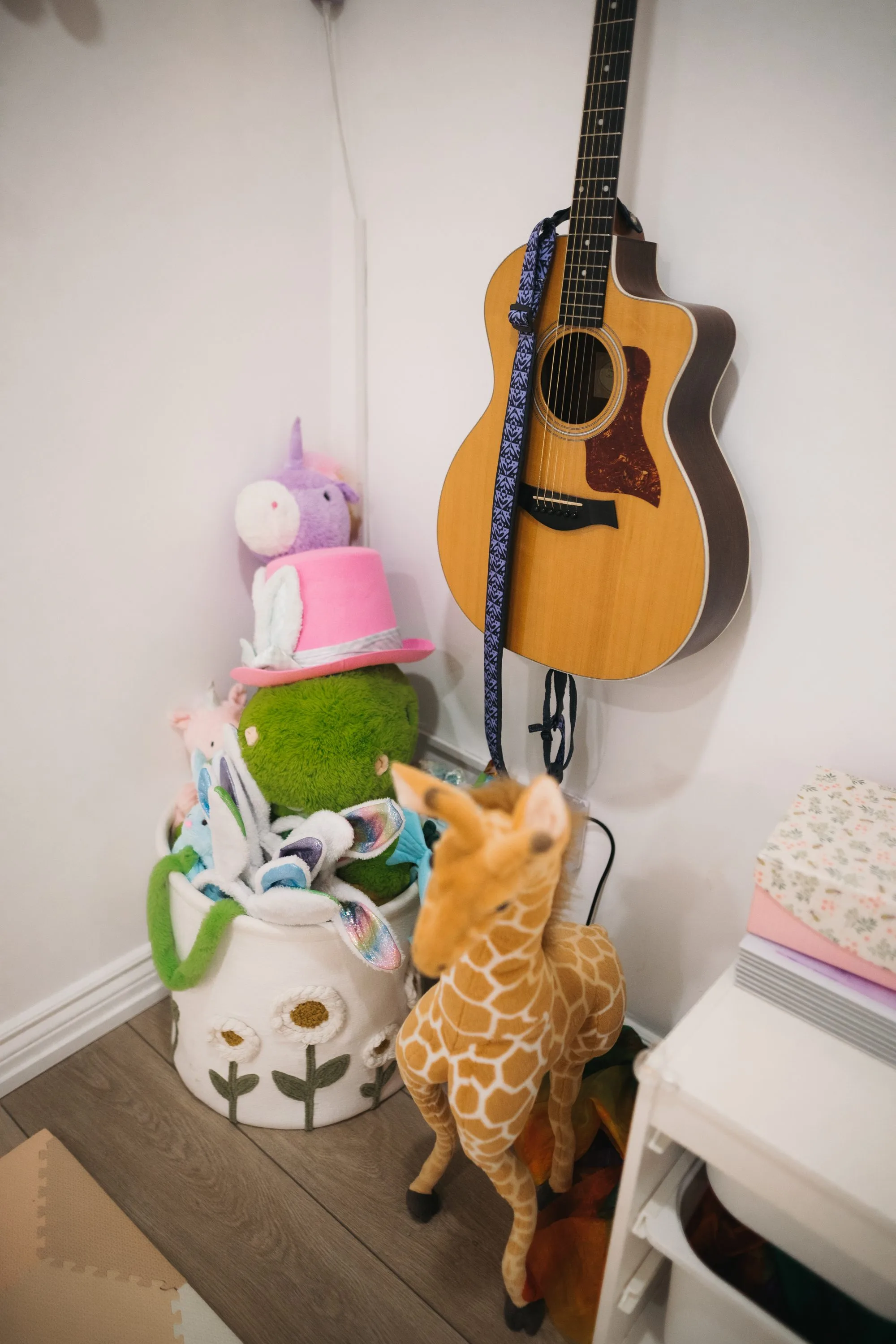 Guitar hanging on the wall surrounded by stuffed animals inside Rockin' with Rach studio Toronto