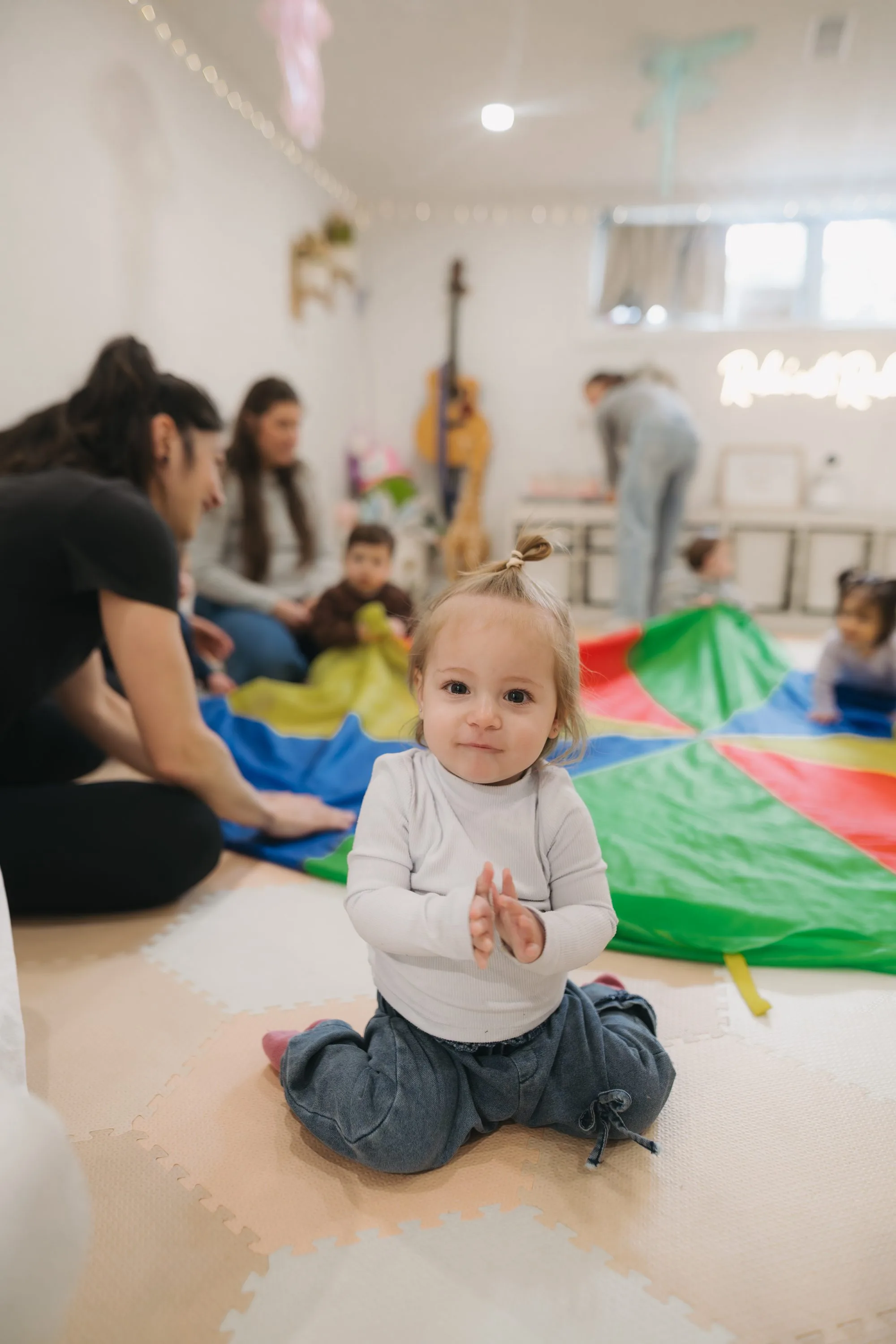 Toddler girl clapping with joy during parachute activity at Rockin' with Rach Toronto